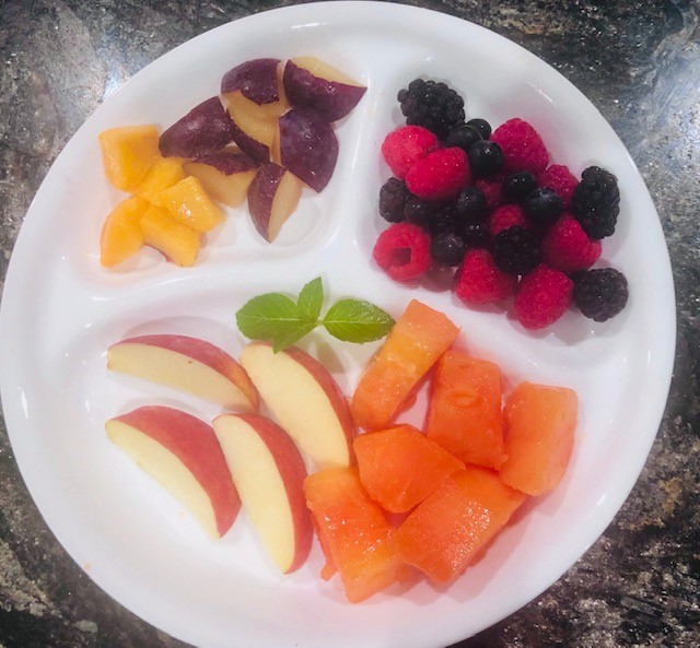 A Plate with 3 sections. Plums and Mangoes in top left, Berries in top right, and the rest at the bottom